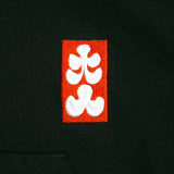 Embroidered white floral design on a red square patch on a black background