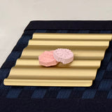 Pink aroma stones on a gold wave tray, styled as a scent display