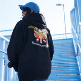 Person wearing a black hoodie with colorful designs and text, standing on blue steps.