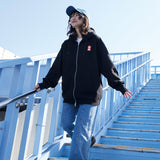 Person wearing a black hoodie with a red logo and blue jeans on a blue staircase.