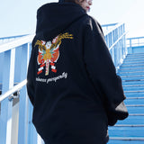 Person wearing a black hoodie with a colorful design on the back, standing on blue steps.