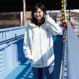 Person wearing a white jacket with a logo on a blue bridge