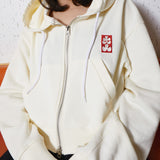 White hoodie with a red logo on the chest against a neutral background